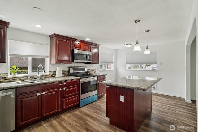 6817 S D St, Tacoma, WA 98408 - kitchen with appliances with stainless steel finishes, reddish brown cabinets, dark wood-type flooring, a kitchen island, and recessed lighting