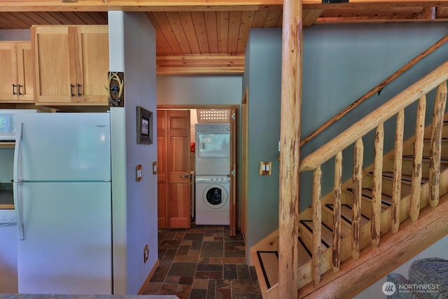 7905 Mountain Home Rd, Leavenworth, WA 98826 - kitchen with freestanding refrigerator, stacked washing machine and dryer, stone finish flooring, wooden ceiling, and light brown cabinetry
