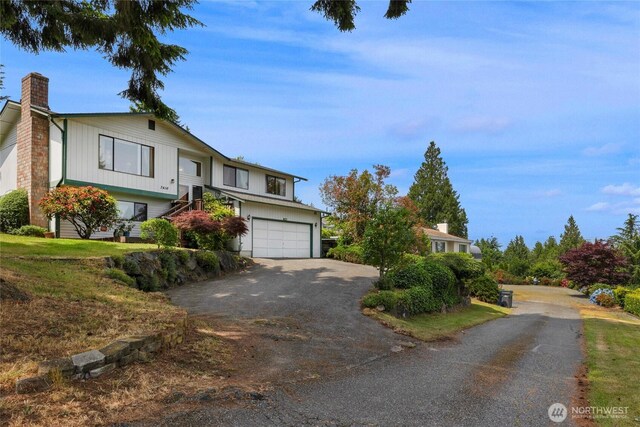 7416 E Heather Way, Everett, WA 98203 - bi-level home featuring a chimney, an attached garage, and driveway