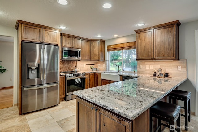 1732 NW 29th Cir, Camas, WA 98607 - kitchen with appliances with stainless steel finishes, a peninsula, light stone counters, decorative backsplash, and recessed lighting