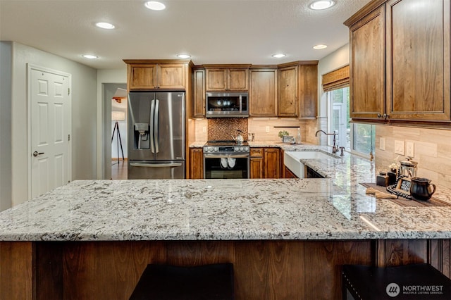 1732 NW 29th Cir, Camas, WA 98607 - kitchen with stainless steel appliances, a peninsula, light stone counters, recessed lighting, and decorative backsplash