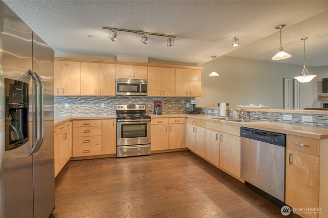 262 Oyhut Bay Blvd SW Unit 204, Ocean Shores, WA 98569 - kitchen featuring appliances with stainless steel finishes, light brown cabinetry, a peninsula, tasteful backsplash, and a textured ceiling