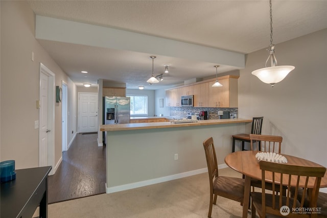 262 Oyhut Bay Blvd SW Unit 204, Ocean Shores, WA 98569 - kitchen featuring appliances with stainless steel finishes, a peninsula, light brown cabinets, light countertops, and tasteful backsplash