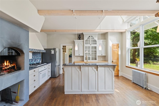 5513 Homestead Ln, Anacortes, WA 98221 - kitchen featuring radiator, freestanding refrigerator, custom exhaust hood, a lit fireplace, and a breakfast bar