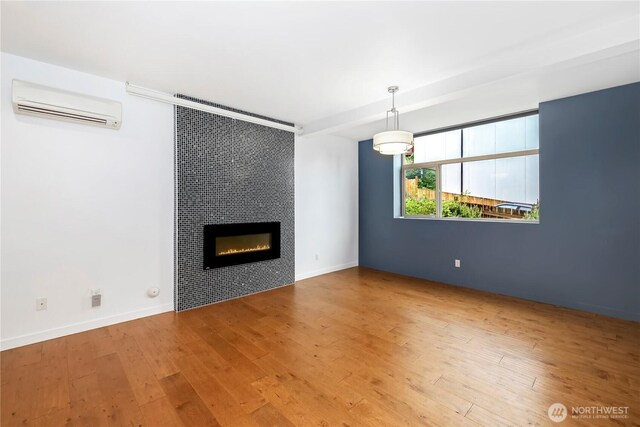7528 21st Ave SW, Seattle, WA 98106 - unfurnished living room with a wall mounted air conditioner, wood finished floors, and a tiled fireplace