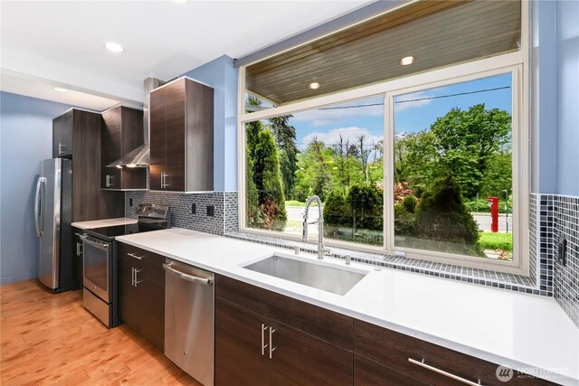 7528 21st Ave SW, Seattle, WA 98106 - kitchen featuring appliances with stainless steel finishes, wall chimney exhaust hood, light countertops, decorative backsplash, and dark brown cabinets