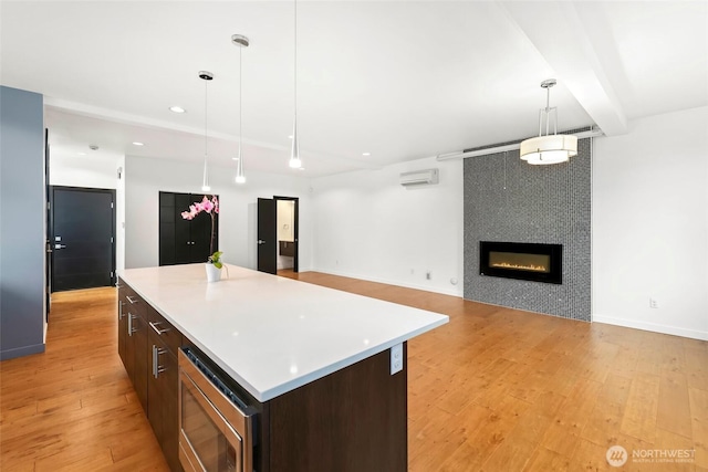 7528 21st Ave SW, Seattle, WA 98106 - kitchen with stainless steel microwave, a wall mounted air conditioner, a kitchen island, light wood-style floors, and light countertops