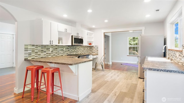 4762 NE Tree Ridge Ln, Poulsbo, WA 98370 - kitchen featuring stainless steel appliances, open shelves, arched walkways, dark countertops, and recessed lighting