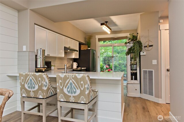 23300 SE Black Nugget Rd Unit J3, Issaquah, WA 98029 - kitchen with freestanding refrigerator, under cabinet range hood, light countertops, light wood finished floors, and a peninsula