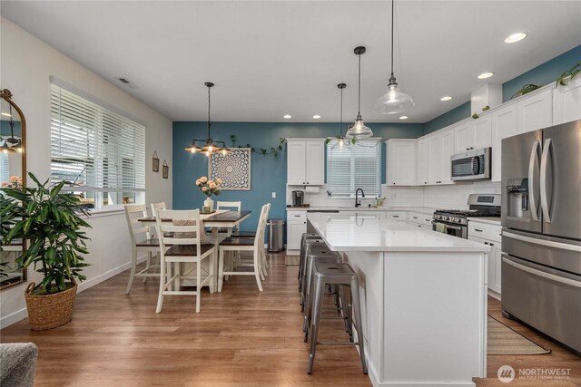 3294 Prill Rd, Centralia, WA 98531 - kitchen with appliances with stainless steel finishes, a center island, a kitchen breakfast bar, white cabinetry, and light wood-type flooring