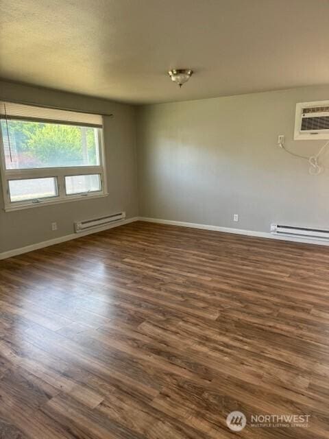 330 SW 5th Ave Unit 336, Ephrata, WA 98823 - empty room featuring a baseboard radiator, dark wood-style flooring, and an AC wall unit