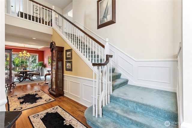 5422 21st Avenue Ct NE, Tacoma, WA 98422 - stairs with a chandelier, wood finished floors, a decorative wall, and a wainscoted wall