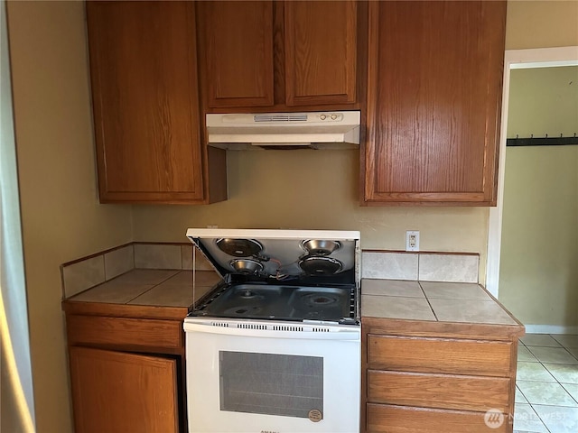 1421 Fairmount Ave, Shelton, WA 98584 - kitchen with under cabinet range hood, tile counters, white electric stove, and tile patterned flooring