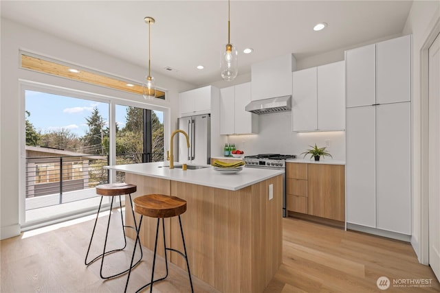 6732 21st Ave SW, Seattle, WA 98106 - kitchen with wall chimney exhaust hood, high quality appliances, modern cabinets, an island with sink, and a kitchen bar