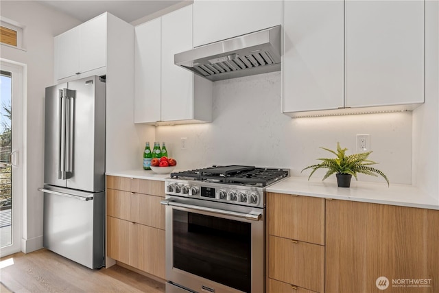 6732 21st Ave SW, Seattle, WA 98106 - kitchen with appliances with stainless steel finishes, wall chimney range hood, light countertops, and light wood-style floors