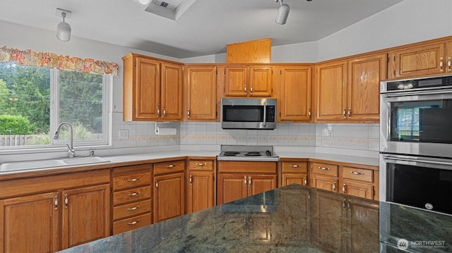 41427 Mountain View Pl E, Gold Bar, WA 98251 - kitchen featuring stainless steel appliances, vaulted ceiling, brown cabinets, backsplash, and a textured ceiling