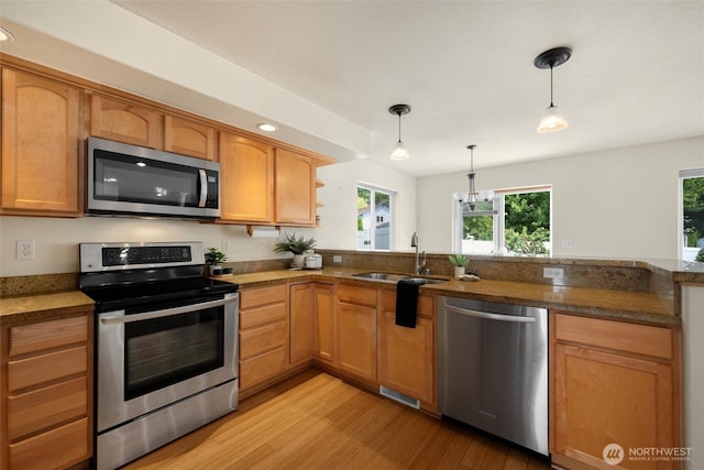 2108 S 18th St, Mount Vernon, WA 98274 - kitchen featuring stainless steel appliances, light wood finished floors, decorative light fixtures, a peninsula, and dark stone countertops