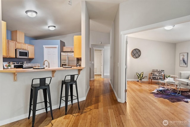 2733 Teal Lake Rd, Port Ludlow, WA 98365 - kitchen featuring appliances with stainless steel finishes, a breakfast bar area, wood finished floors, and a peninsula