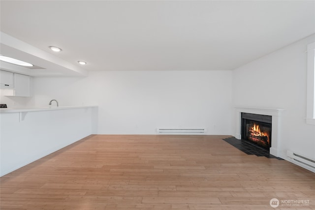6055 35th Ave SW Unit 308, Seattle, WA 98126 - unfurnished living room featuring a baseboard heating unit, a fireplace with flush hearth, light wood-type flooring, and recessed lighting