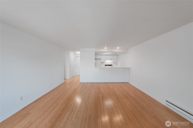 6055 35th Ave SW Unit 308, Seattle, WA 98126 - unfurnished living room featuring baseboard heating, light wood finished floors, and recessed lighting