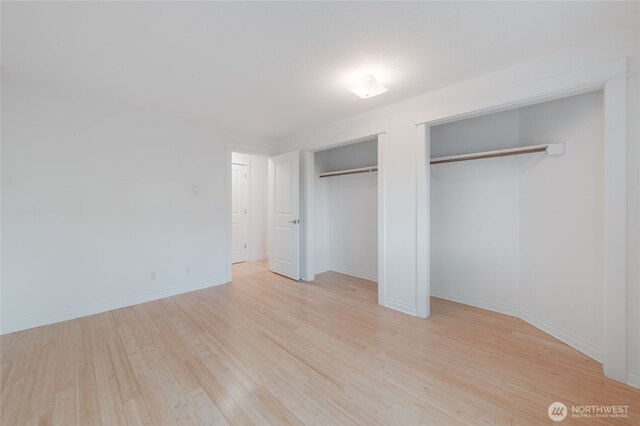 6055 35th Ave SW Unit 308, Seattle, WA 98126 - unfurnished bedroom with multiple closets and light wood-style floors