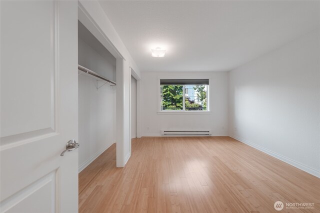 6055 35th Ave SW Unit 308, Seattle, WA 98126 - unfurnished bedroom featuring baseboard heating, light wood-style floors, and a closet