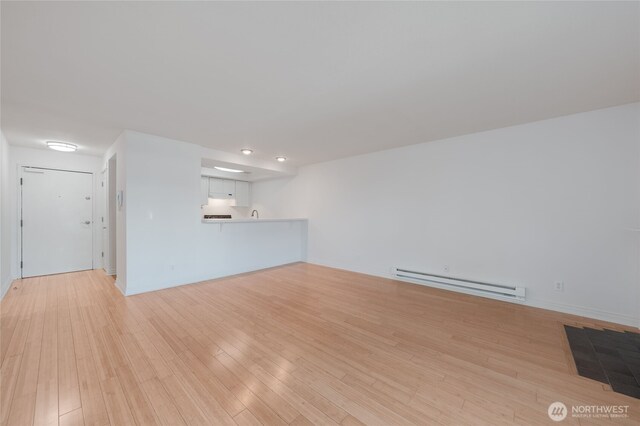 6055 35th Ave SW Unit 308, Seattle, WA 98126 - unfurnished living room with baseboard heating and light wood-style floors