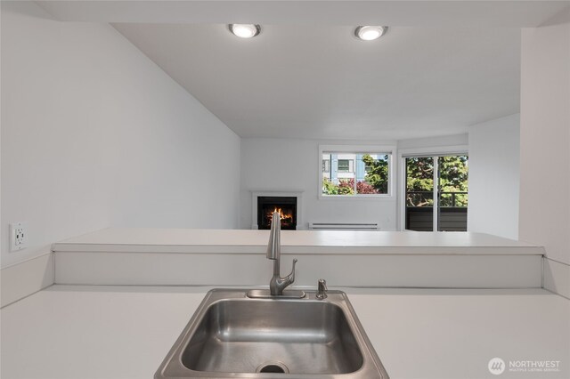 6055 35th Ave SW Unit 308, Seattle, WA 98126 - kitchen with a lit fireplace, a baseboard radiator, recessed lighting, light countertops, and open floor plan
