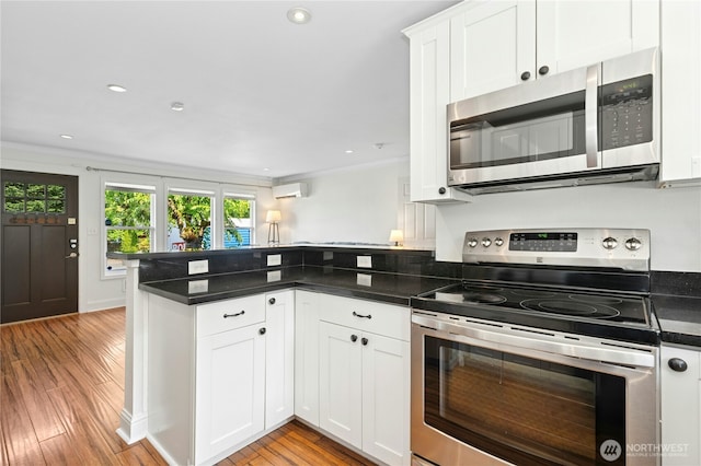 9359 SW 31st Pl, Seattle, WA 98126 - kitchen featuring stainless steel appliances, a peninsula, light wood-style flooring, white cabinets, and a wall mounted AC