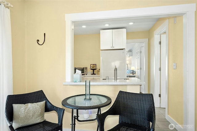 9359 SW 31st Pl, Seattle, WA 98126 - kitchen featuring freestanding refrigerator, white cabinetry, light tile patterned floors, light countertops, and a kitchen breakfast bar