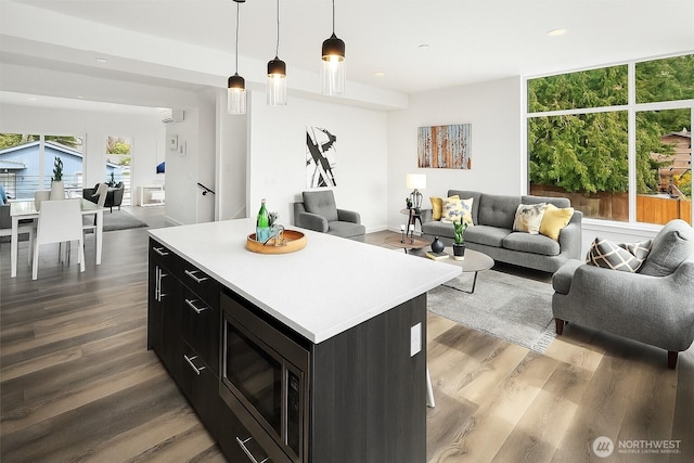 16547 NE 92nd Pl Unit 6A, Redmond, WA 98052 - kitchen featuring stainless steel microwave, dark cabinetry, open floor plan, dark wood finished floors, and light countertops