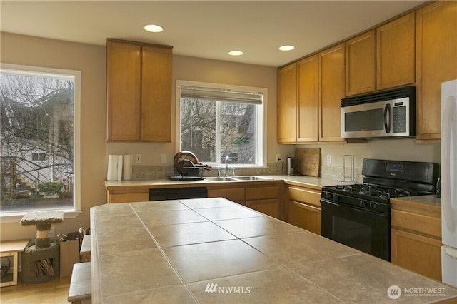 5223 11th Ave NE Unit A, Seattle, WA 98105 - kitchen with black range with gas cooktop, stainless steel microwave, tile counters, recessed lighting, and brown cabinets