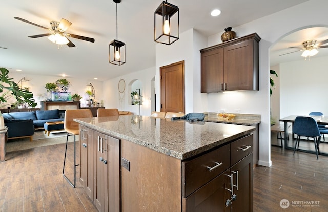 14410 99th Way SE, Yelm, WA 98597 - kitchen featuring a ceiling fan, a kitchen breakfast bar, open floor plan, a kitchen island, and light stone countertops
