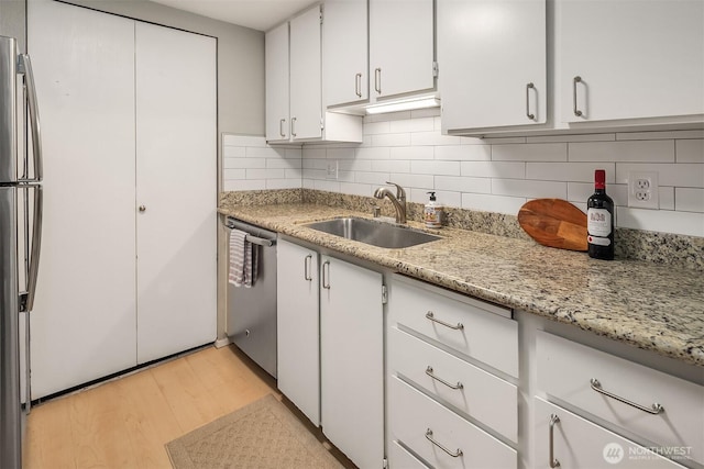 12023 100th Ave NE Unit C4, Kirkland, WA 98034 - kitchen featuring stainless steel appliances, light wood-style floors, decorative backsplash, white cabinetry, and light stone counters