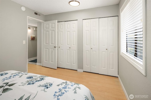 12023 100th Ave NE Unit C4, Kirkland, WA 98034 - bedroom with multiple closets, light wood-style flooring, and a textured ceiling