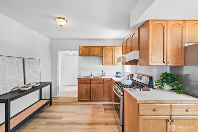 6719 46th Ave S, Seattle, WA 98118 - kitchen with gas stove, under cabinet range hood, light wood-style flooring, and light countertops