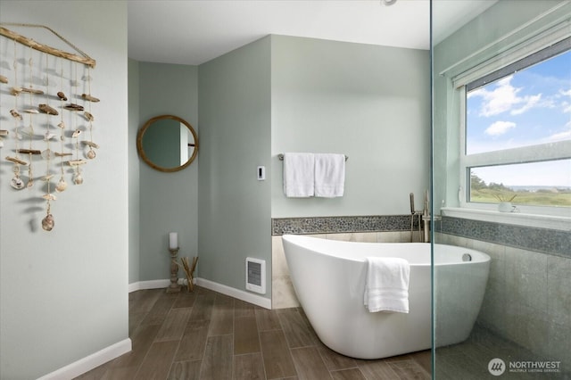 179 Perry Dr, Coupeville, WA 98239 - bathroom with a freestanding tub, tile walls, wood tiled floors, and a wainscoted wall