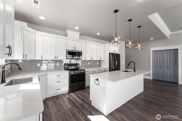 1300 W Marina Dr Unit 33, Moses Lake, WA 98837 - kitchen featuring appliances with stainless steel finishes, backsplash, dark wood-style flooring, a center island with sink, and white cabinets