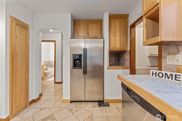 123 Scenic View Dr, Longview, WA 98632 - kitchen featuring appliances with stainless steel finishes, backsplash, arched walkways, light countertops, and light tile patterned floors