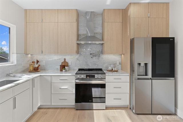 320 NW 51st St Unit A, Seattle, WA 98107 - kitchen featuring appliances with stainless steel finishes, wall chimney range hood, light brown cabinets, and light wood-style flooring