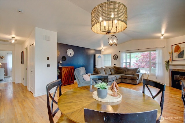 4031 Alyssa Ct, Bellingham, WA 98226 - dining space featuring vaulted ceiling, light wood-style floors, a chandelier, and a glass covered fireplace