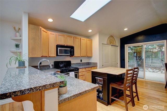 4031 Alyssa Ct, Bellingham, WA 98226 - kitchen featuring appliances with stainless steel finishes, light brown cabinetry, light wood-style flooring, vaulted ceiling, and a peninsula