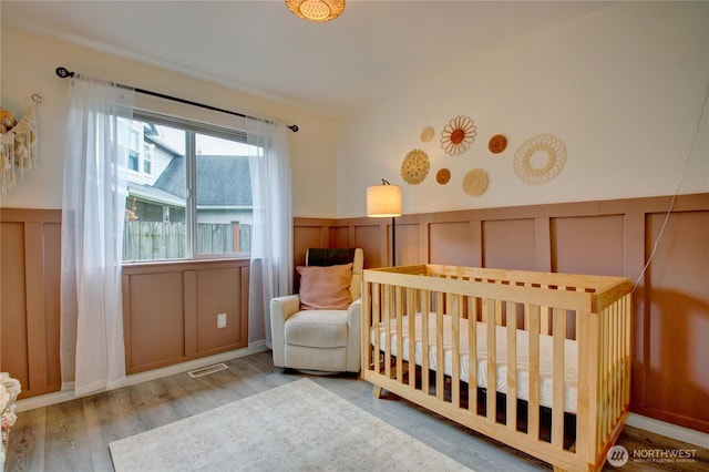 4031 Alyssa Ct, Bellingham, WA 98226 - bedroom with a decorative wall, a nursery area, wood finished floors, and wainscoting