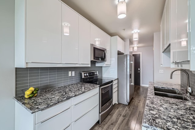 655 Crockett St Unit B304, Seattle, WA 98109 - kitchen with appliances with stainless steel finishes, white cabinets, wood finished floors, decorative backsplash, and dark stone countertops