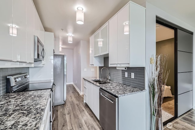 655 Crockett St Unit B304, Seattle, WA 98109 - kitchen with stainless steel appliances, light stone counters, decorative backsplash, light wood-type flooring, and white cabinetry