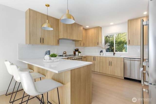 2216 18th Ave S, Seattle, WA 98144 - kitchen featuring appliances with stainless steel finishes, light brown cabinets, a peninsula, a breakfast bar, and backsplash