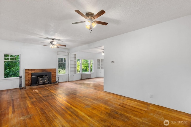 212 SE Cowlitz Rd, Winlock, WA 98596 - unfurnished living room featuring radiator heating unit, a wood stove, a ceiling fan, a textured ceiling, and wood-type flooring