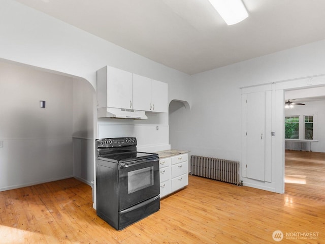 212 SE Cowlitz Rd, Winlock, WA 98596 - kitchen featuring black electric range, radiator heating unit, under cabinet range hood, arched walkways, and white cabinetry