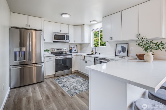 1415S 93rd St, Tacoma, WA 98444 - kitchen featuring stainless steel appliances, a peninsula, light countertops, light wood-style floors, and white cabinetry