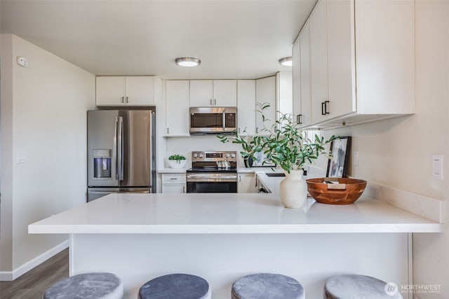 1415S 93rd St, Tacoma, WA 98444 - kitchen with appliances with stainless steel finishes, light countertops, a peninsula, and wood finished floors